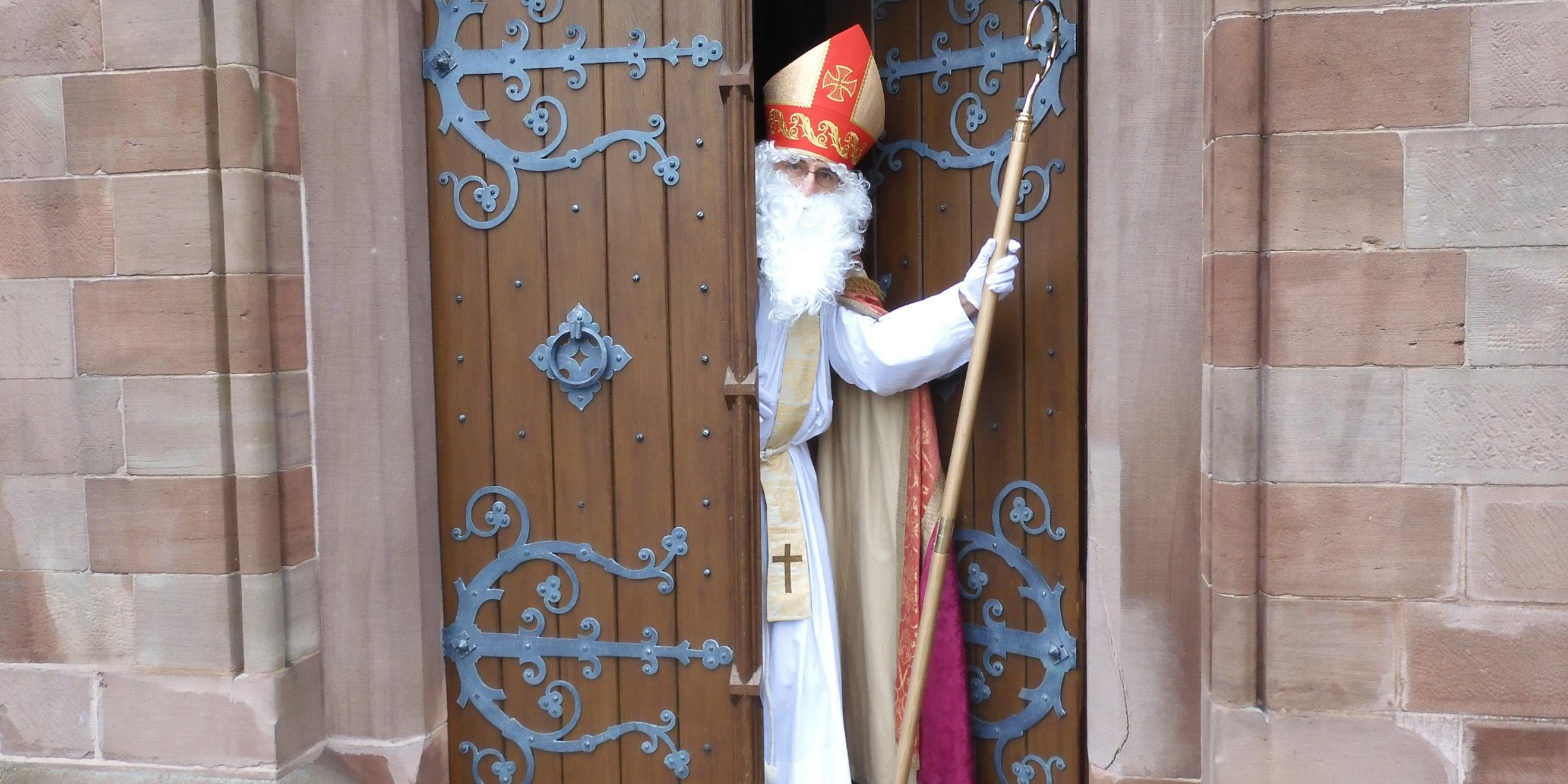 Ein verkleideter Nikolaus kommt aus einer Kirchentüre einem entgegen